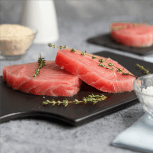 Steak de atún crudo, corte grueso, sobre tabla con romero fresco