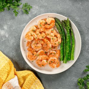 Camarones salteados con especias servidos con espárragos a la plancha